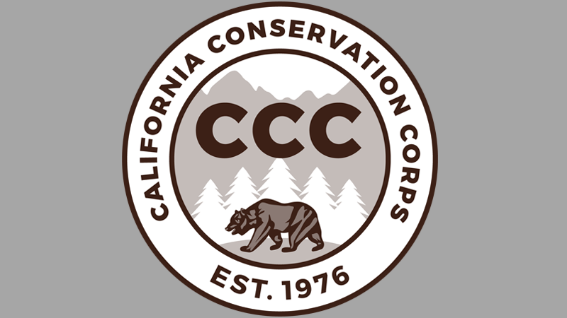 California Conservation Corps logo. Reads: California Conservation Corps, CCC, established 1976. Image is single color of brown. Depicts wording in a circle, inside circle is a mountain range, CCC in large letters, pine trees in front of the mountains, and a California grizzly bear walking across grass.