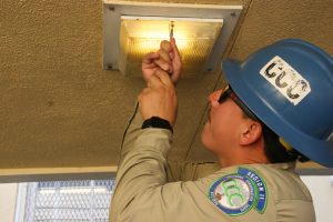 Corpsmember using screwdriver to open light fixture