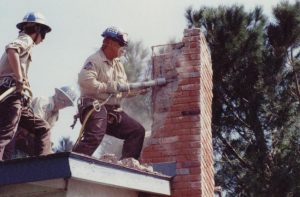 Corpsmembers use pneumatic equipment to tear down damaged chimney of home in Santa Clarita area