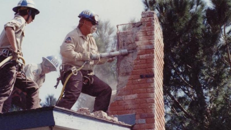 Corpsmembers use pneumatic tool to remove bricks from damaged chimney