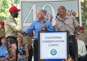 Corpsmember shakes hands with Gov. Jerry Brown with Director Bruce Saito standing next to him