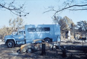 Blue CCC crew vehicle parked in fire ravaged neighborhood