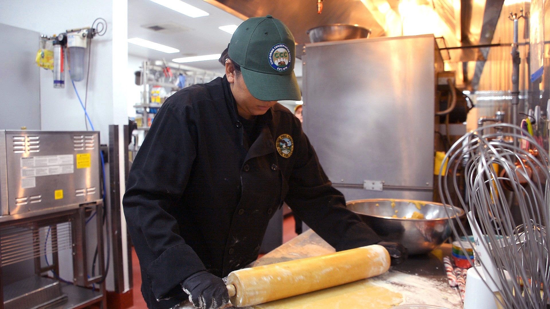 female culinary coprsmember uses rolling pin in kitchen