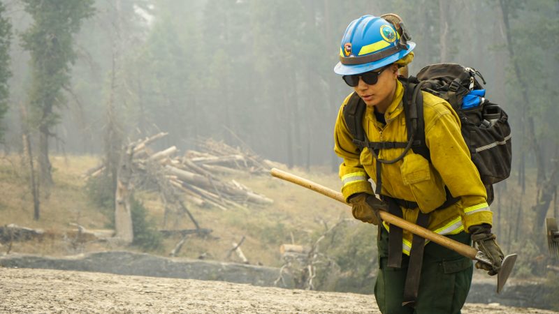 Wildland firefighter corpsmember hikes up hill.