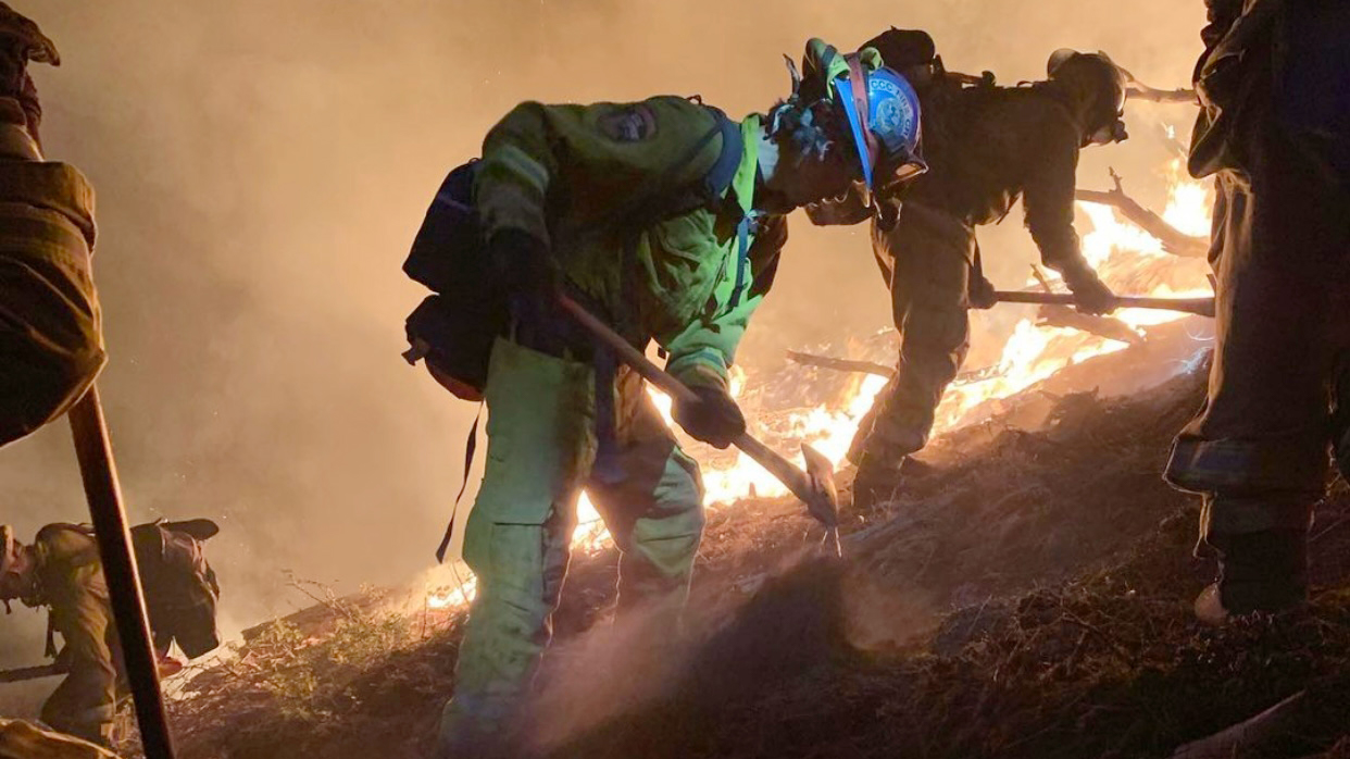 female corpsmember profile as fire burns in the background