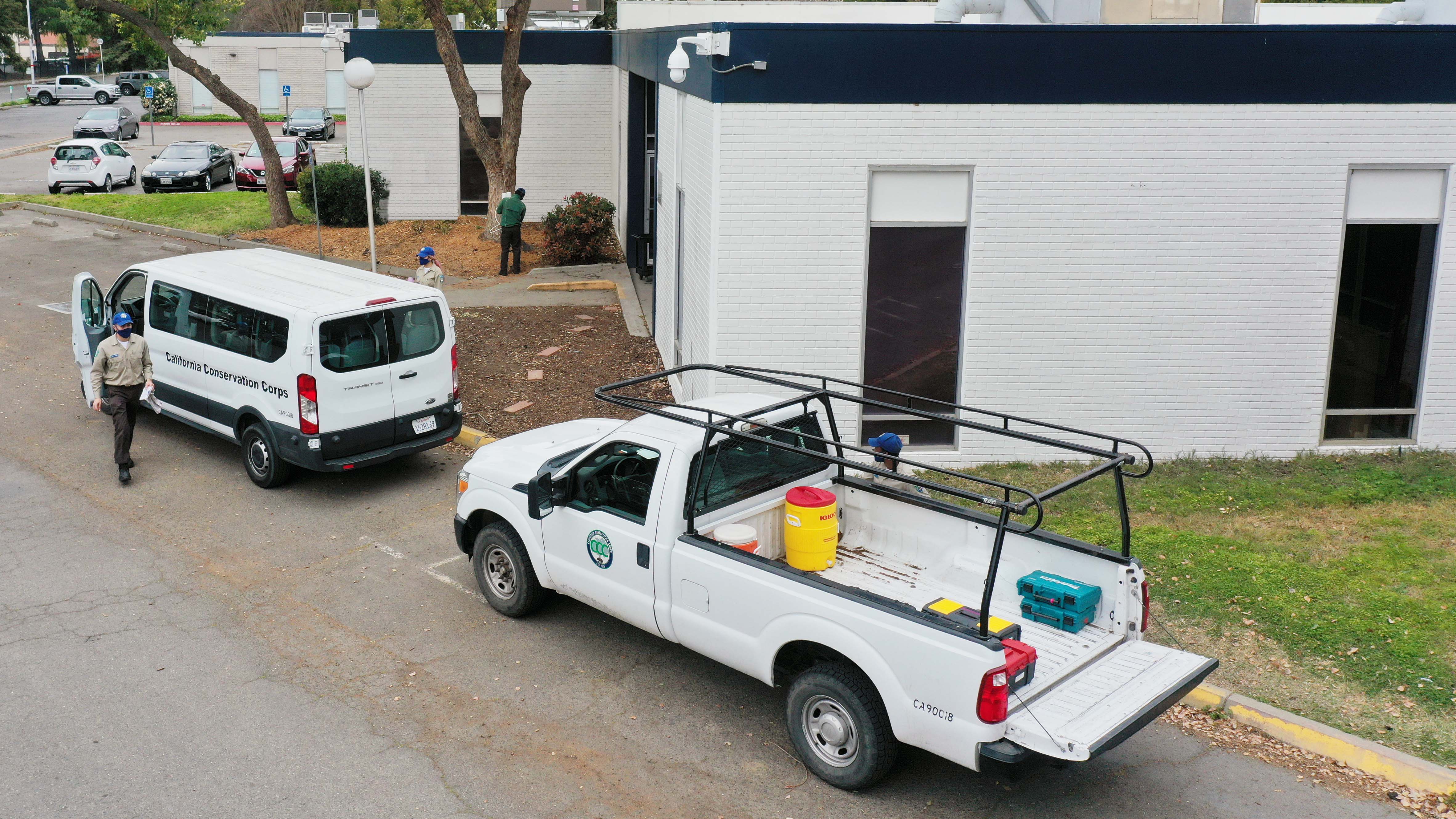 two vehicles outside a building with people walking around