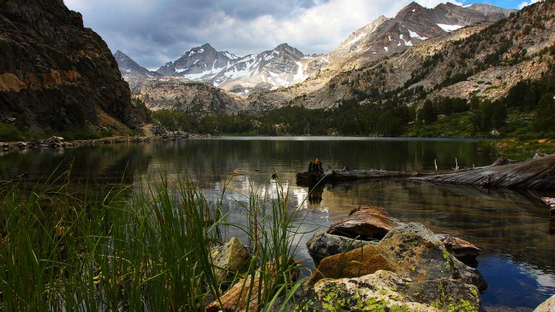 Photo of backcountry lake, water in the foreground, mountains in the deep background