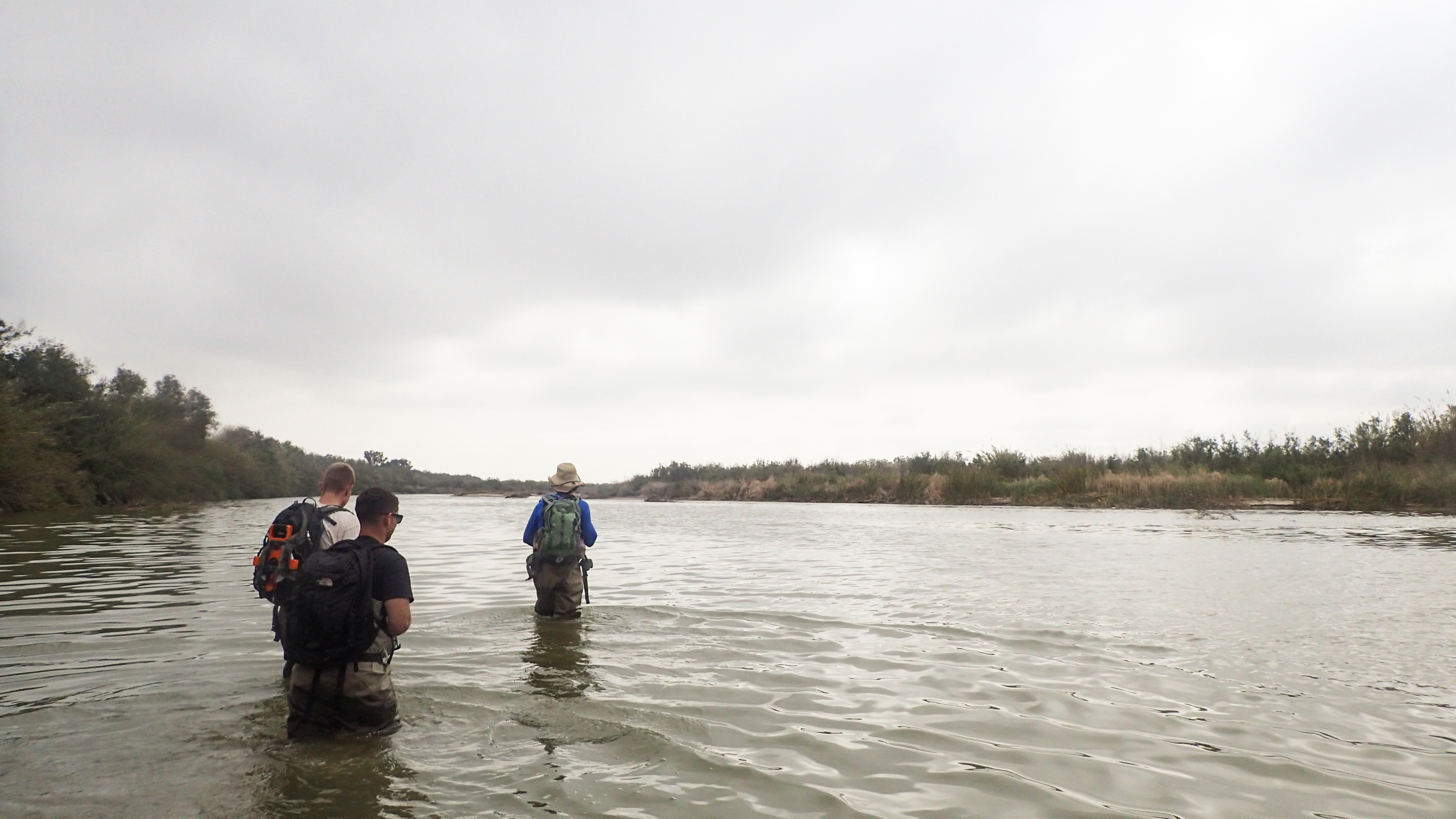 corpsmembers standing in creek beneath gloomy sky