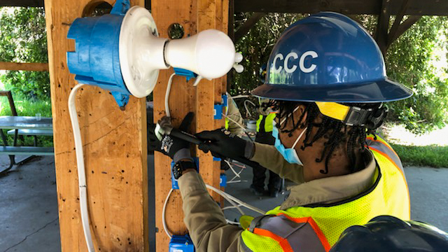 man in safety gear uses screw driver to attach electrical box to stud