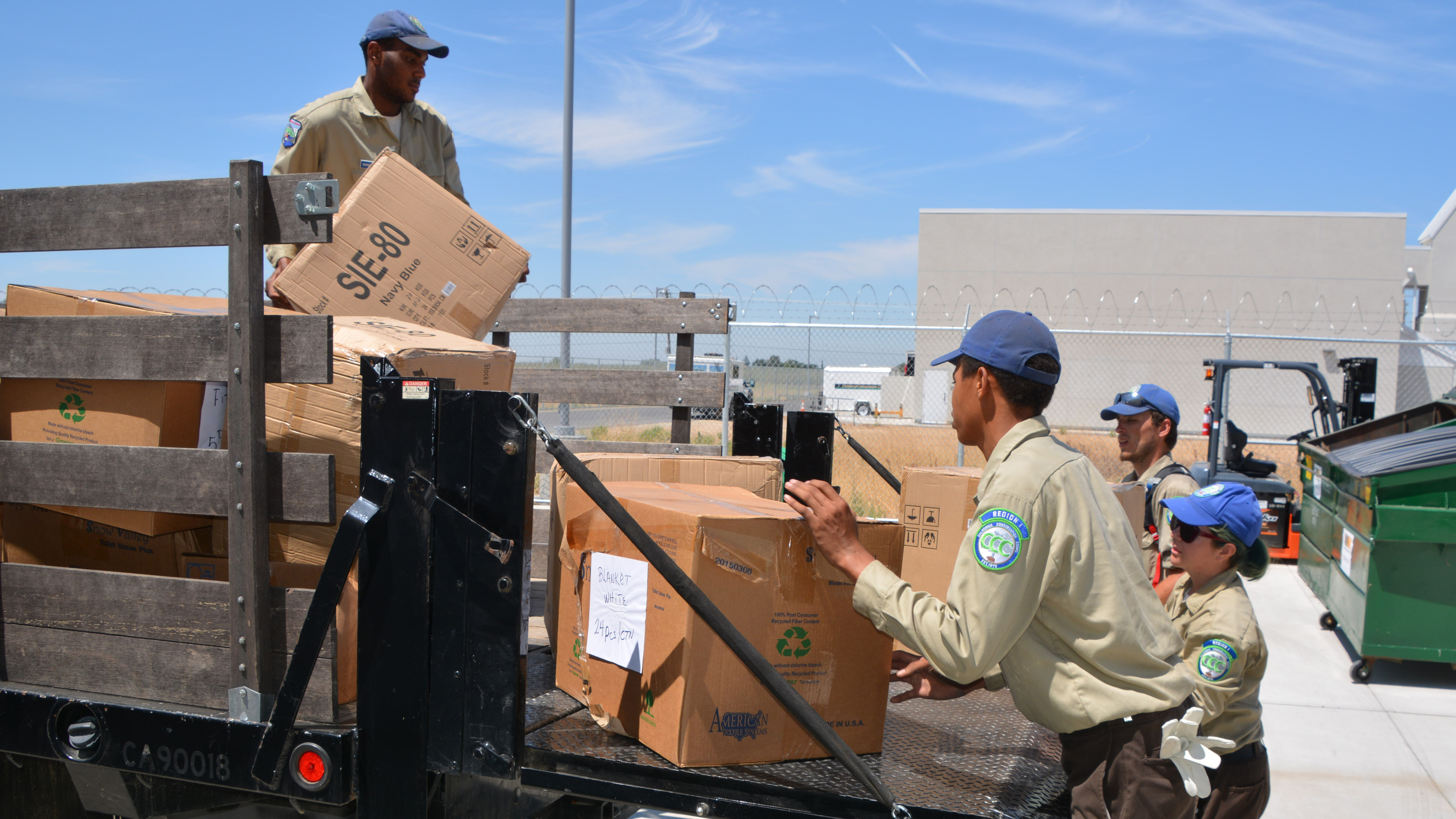 Delta Corpsmembers unloading boxes from a truck bed.