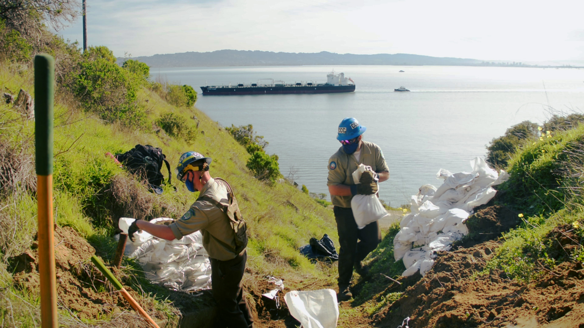 Corpsmembers haul sand bags atop island