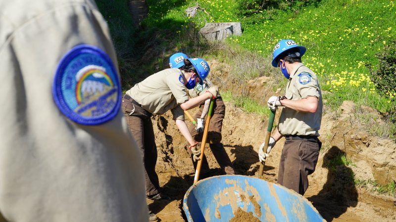 CCC Siskiyou corpsmembers using shovels to remove dirt from a drain