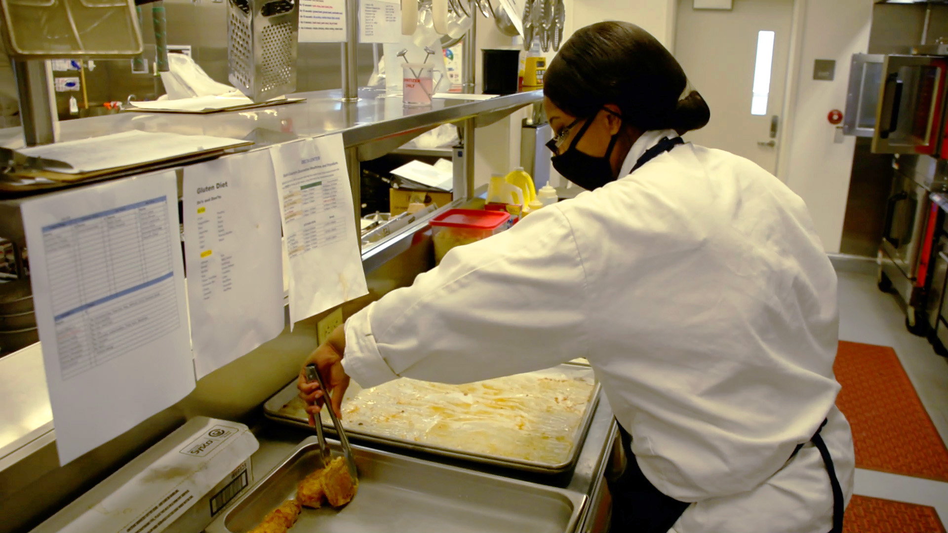 female corpsmember in kitchen uses utensil to prepare food