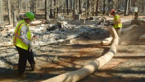 CCC Chico Crew Leader places a straw wattle into place around a burned home