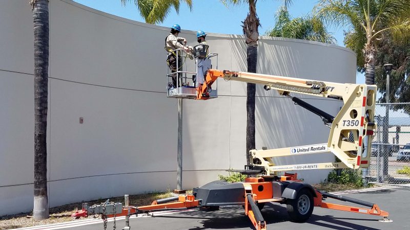 two corpsmembers elevated in aerial boom lift working on parking lot light fixture