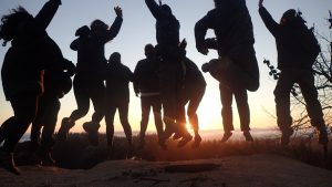 people jumping while sun setting
