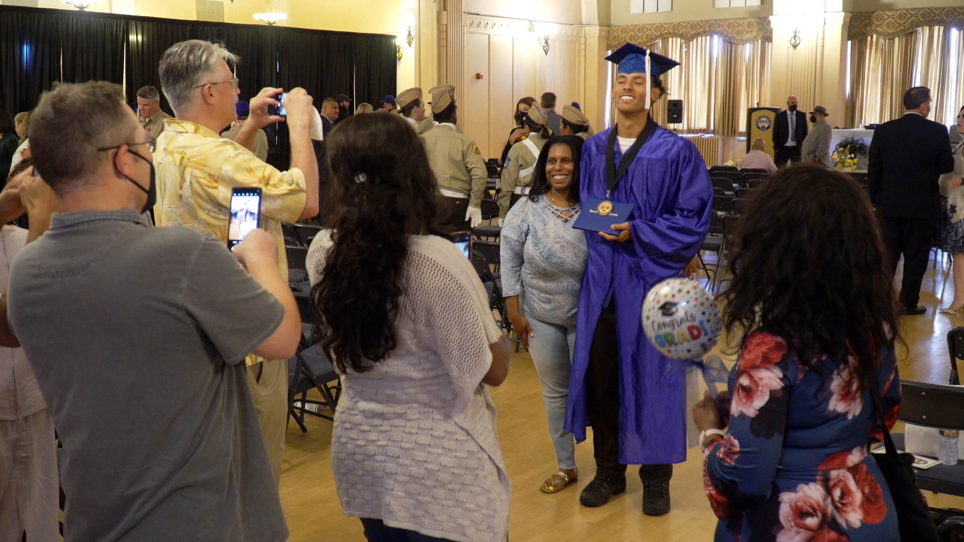 man in graduation gown celebrates with family