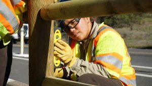 woman holding level against fence post