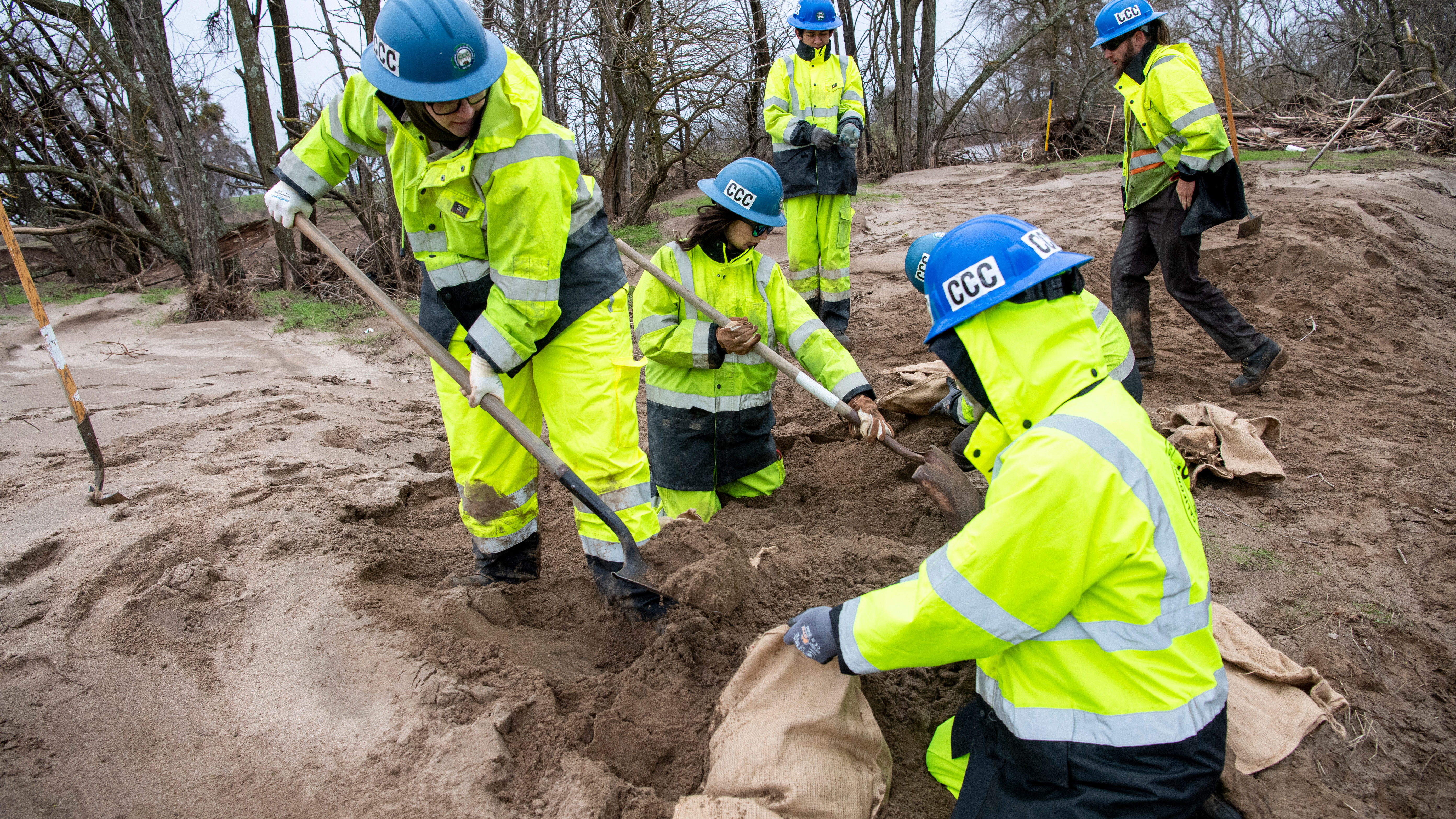 corpsmembers using shovels to fill sand bags