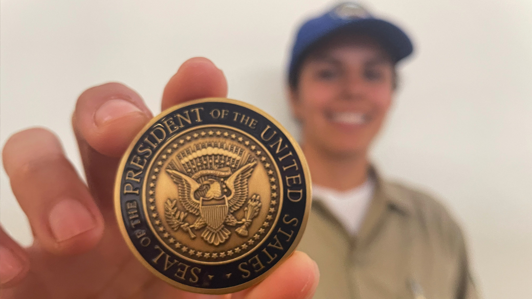 female blurred out in background holding presidential challenge coin