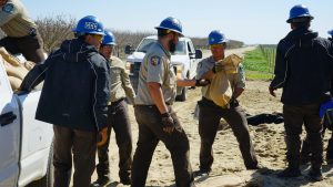 corpsmembers in uniform passing sand bags to each other