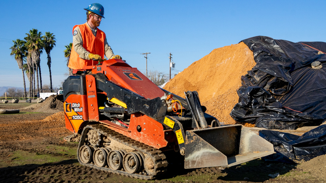 corpsmember driving a skid steer
