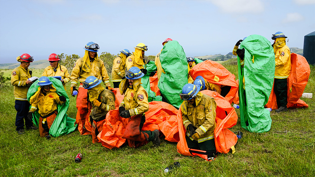 firefighters emerging from training shelters on grassy hill