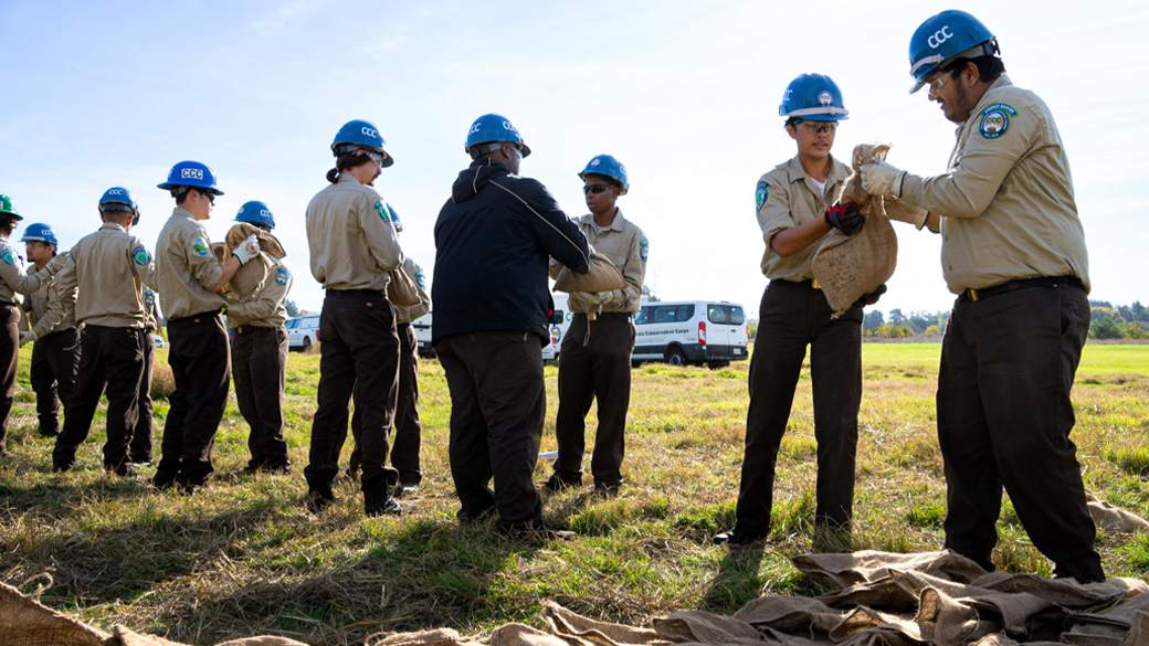 Corpsmembers passing sandbags in grass field