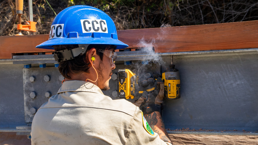corpsmember using drill to secure wood to a steel beam
