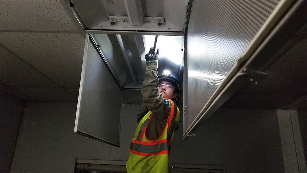 female with headlap on helmet removes old fluorescent light