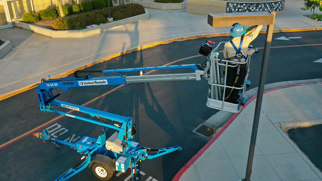 Corpsmember on a mounted boom lift replacing light fixture.