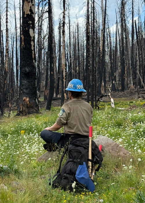 A Corpsmember sits across from the Carr Fire Burn Scar. 