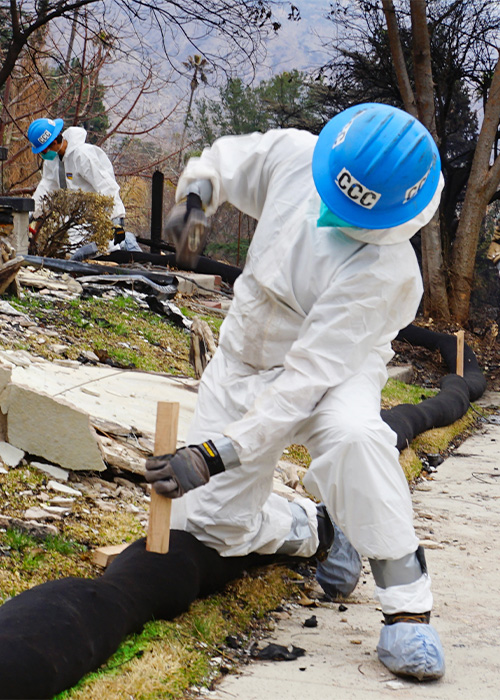 SideImage_SanDiego_500x700 San Diego Corpsmember in full PPE hammers in a stake to secure a silt sock.