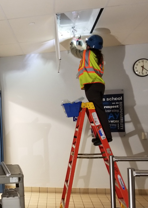 SideImage_Vista_500x700 Corpsmember on ladder replacing light fixture.