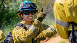 female in fire gear making hand gestures
