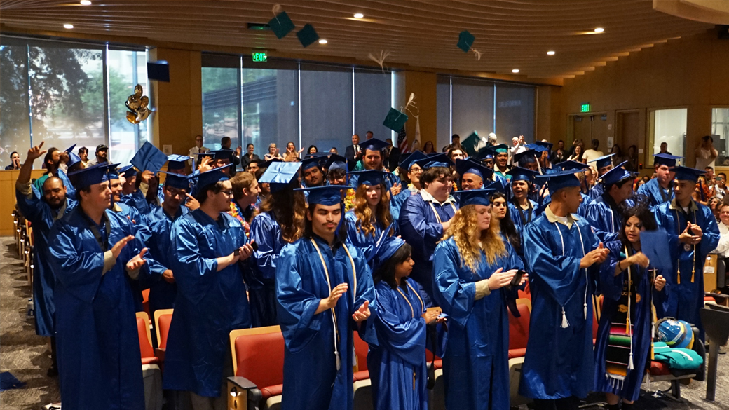 high school graduates throw hats in the air