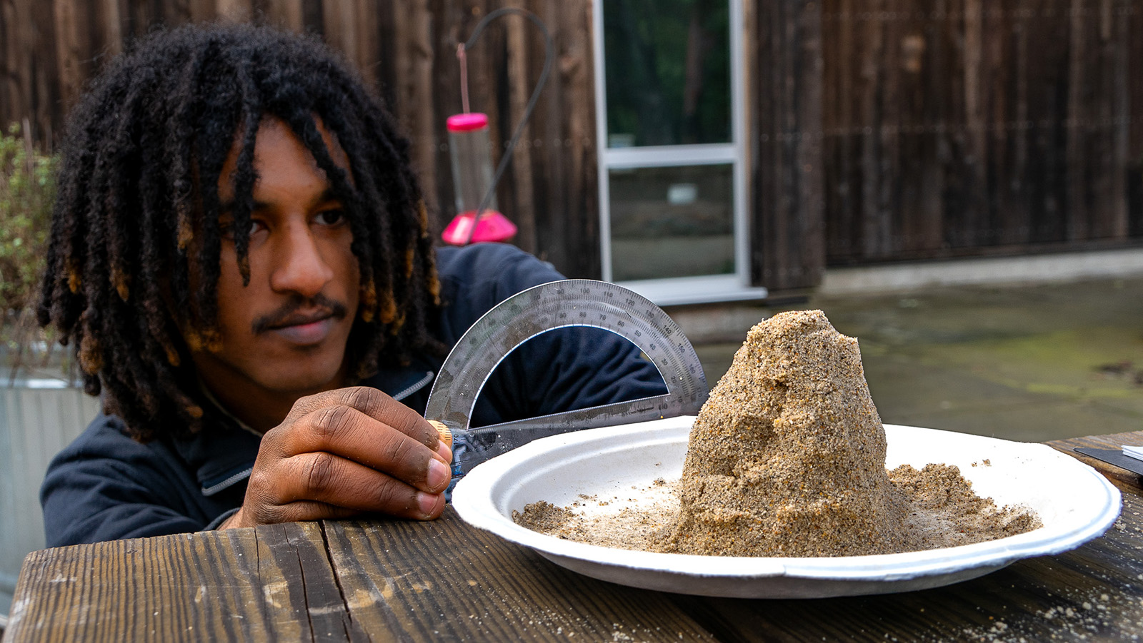 man holding protractor with sand in foreground