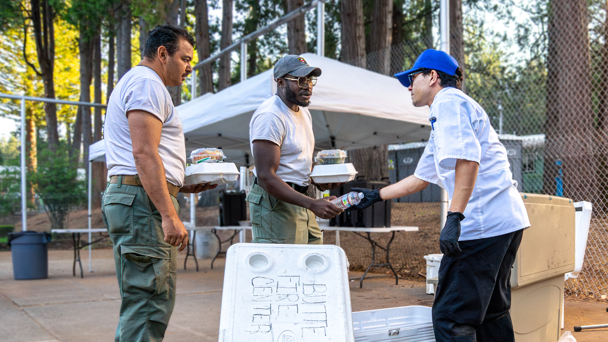 CCC Corpsmember, Aiden Gonzalez, provides water to Cal Guard firefighters who were dispatched to the Park Fire.