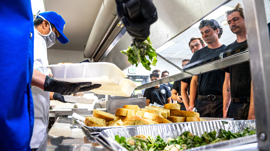counter level view point with salad and bread in the foreground as firefighters wait in line for food in the background
