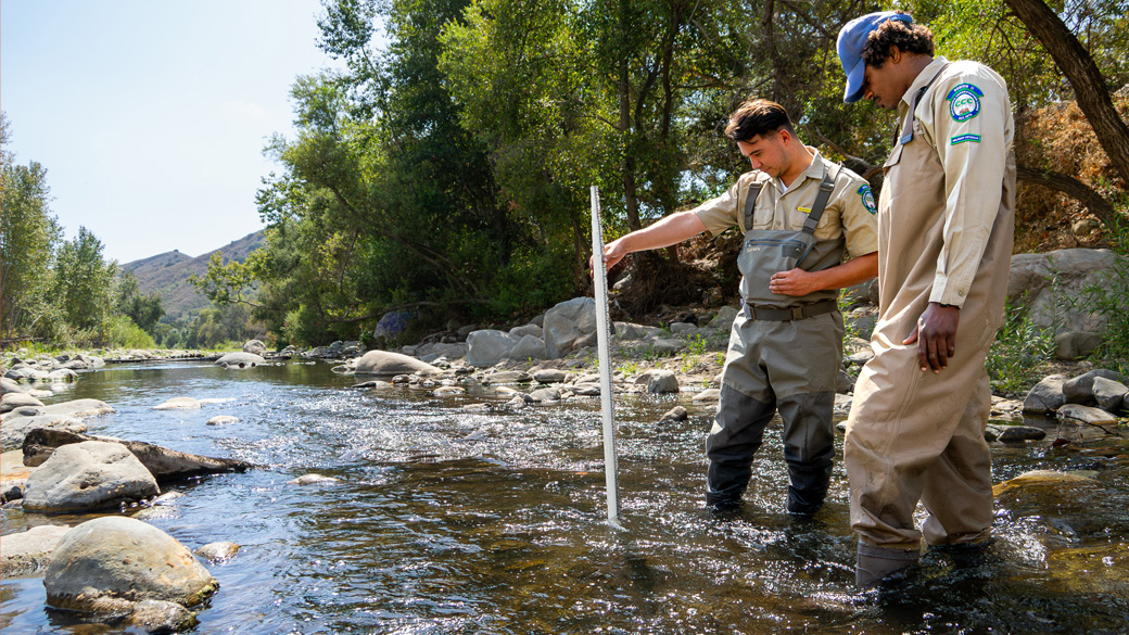 veterans stading in creek using stadia rod