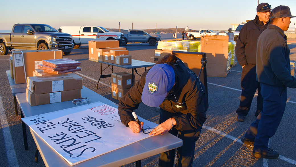 corpsmember writing a sign on a table in front of equipment