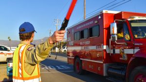 man holding flashlight pointing with a vehicle in the background