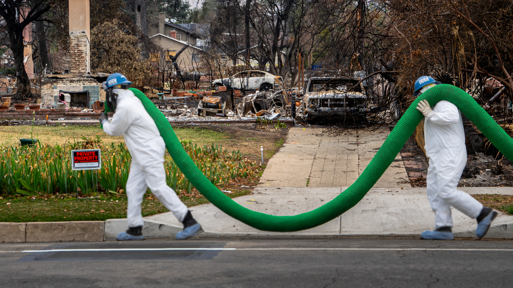 Two Corpsmembers carry a compost sock in Altadena, CA .