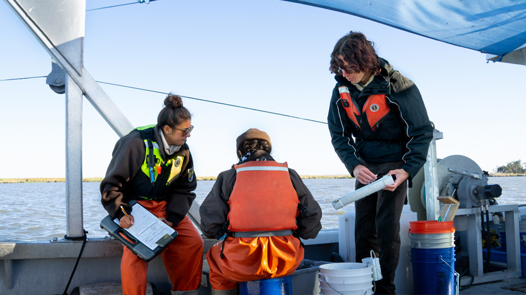 three people on the back of a boat holding clipboard