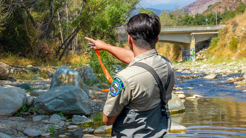 man standing in creek pointing away from camera