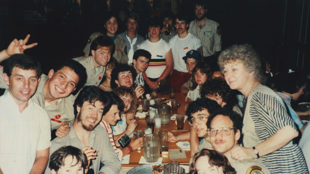 large group of people sitting and standing around the table looking at the camera