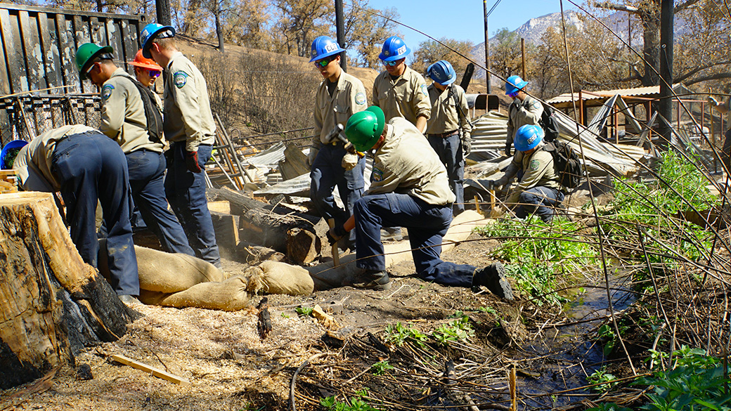Corpsmembers placing silt sock next to a creek.