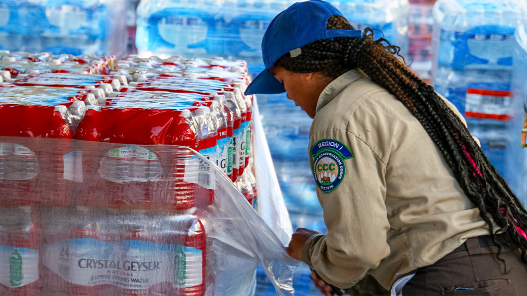 Corpsmember at basecamp, unpacking a pallet of waters.
