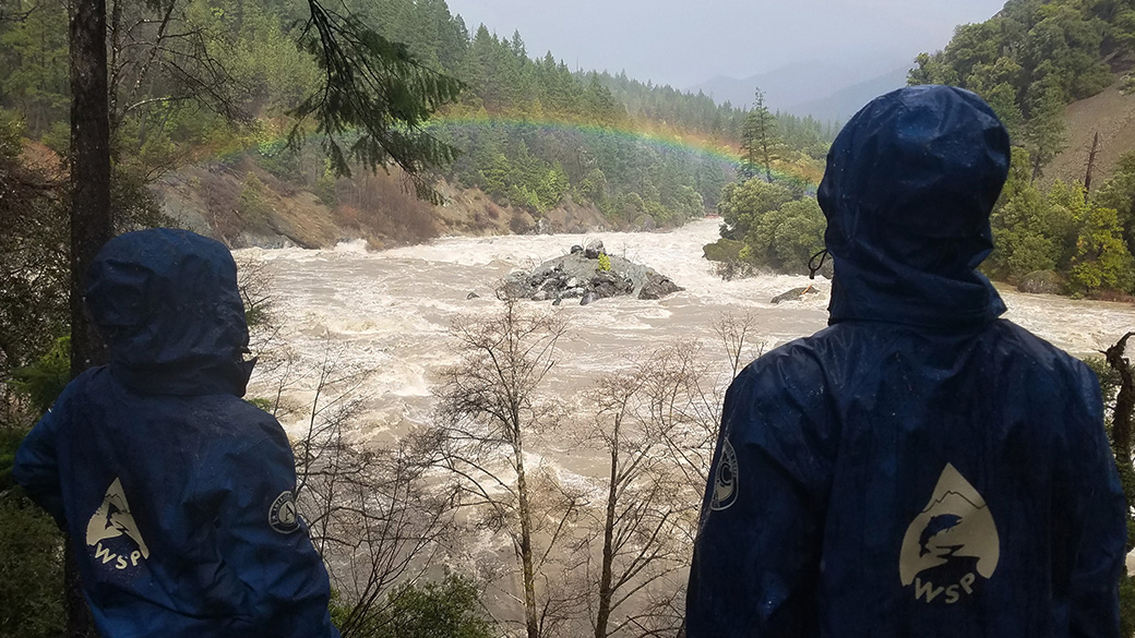 Two WSP Corpsmembers watch a rainbow over a river. 