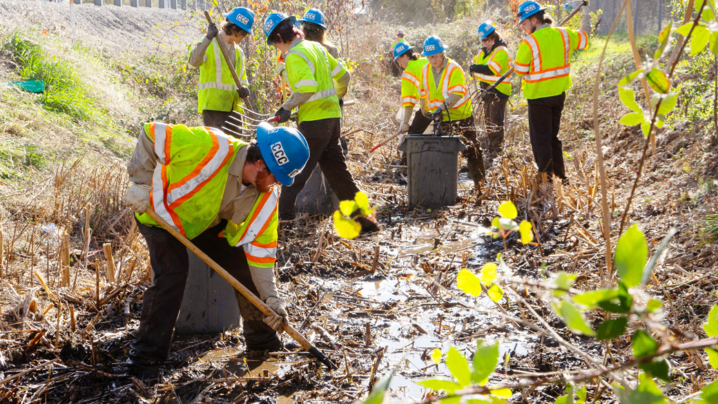 corpsmembers using shovels in mud covered culvert